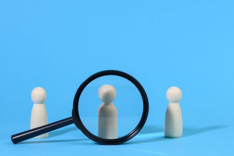 wooden figures of men stand on a blue background and a black mag